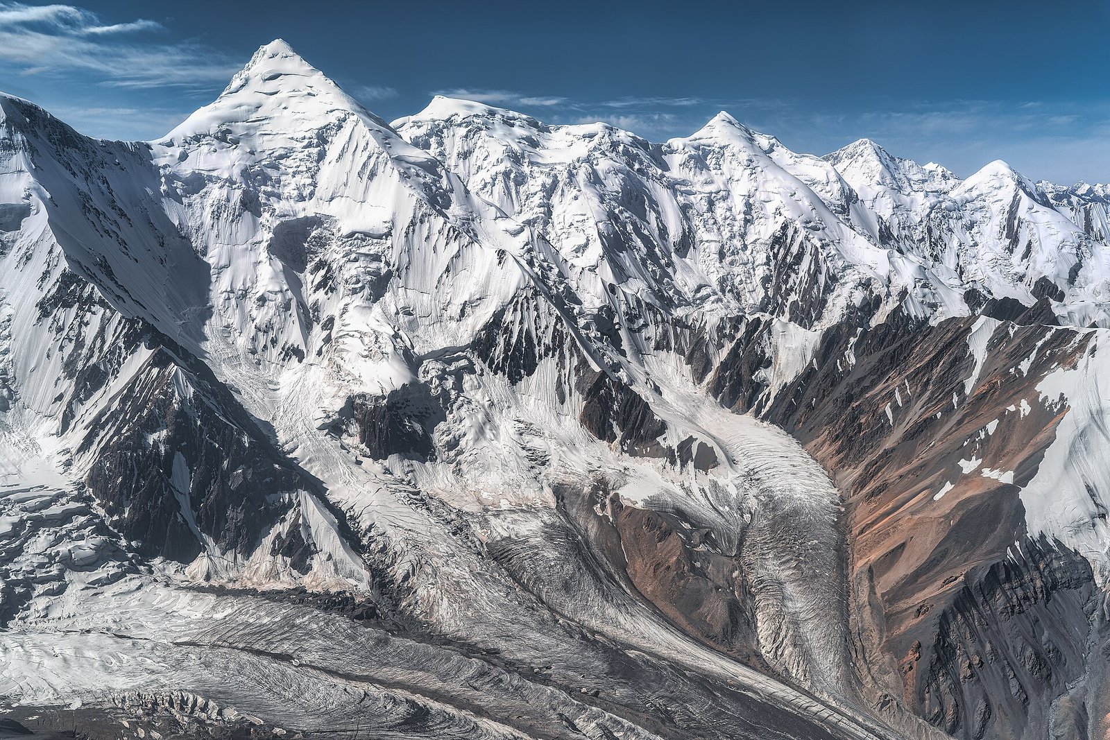 Aerial view from a helicopter over the South Engilchek Glacier area in the Central Tian Shan, Kyrgyzstan. The photograph shows snow-covered mountain peaks, steep glaciated slopes, and glacier tributar