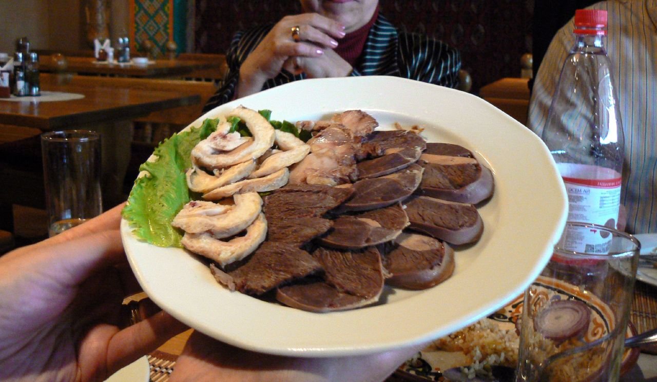 A platter of horse meat served at Kishlak, an Uzbek restaurant in Kazakhstan. The horse meat was served cold. There are three types on the platter: tripe on the left, roasted in the middle, and sausag